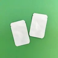 two empty white foil mini pouches with tear notch and rounded corners